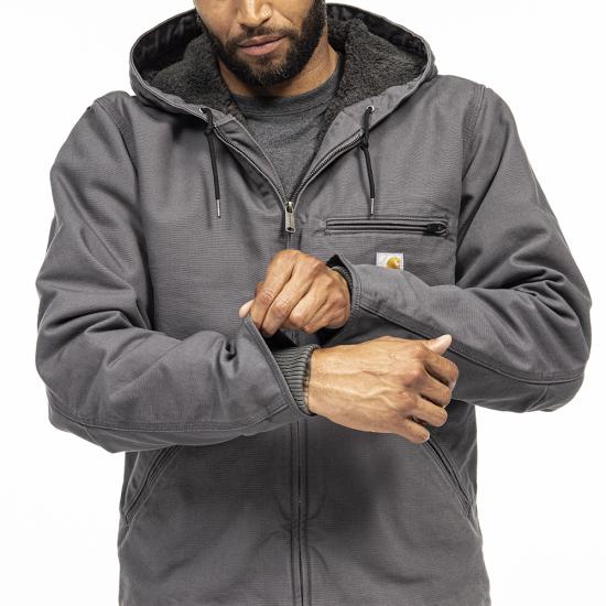 Model adjusting the rib-knit storm cuff on a gray Carhartt Washed Duck Sierra Jacket 104392